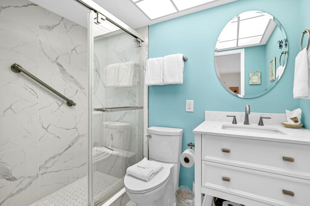 Badezimmer mit Glasdusche, Marmorfliesen und Lavabo